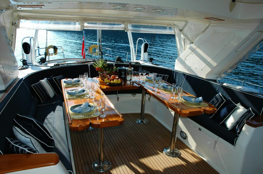 Luxurious yacht deck with an elegantly set dining table overlooking the tranquil sea.